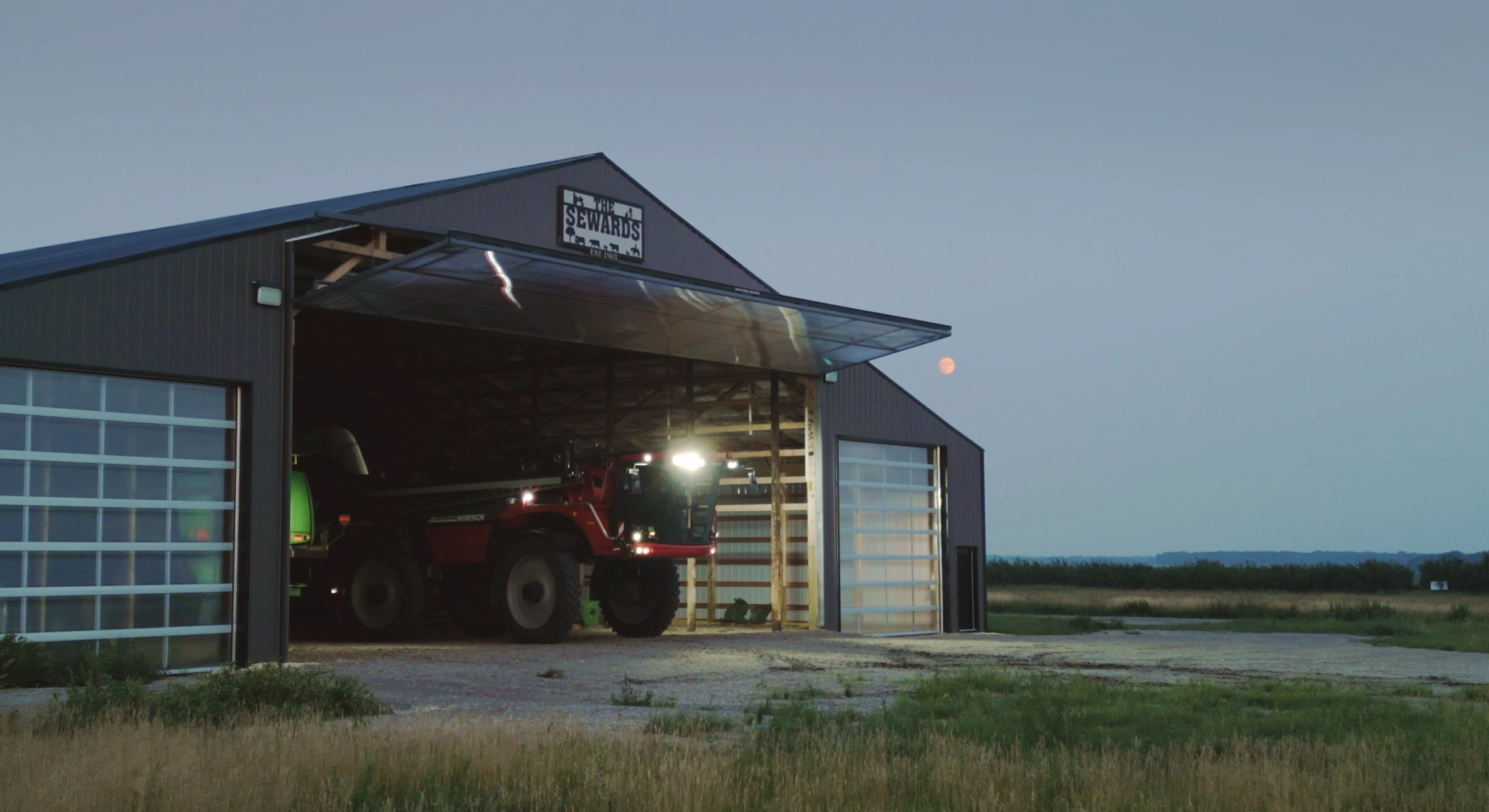 Open bifold door on post frame building at dusk.